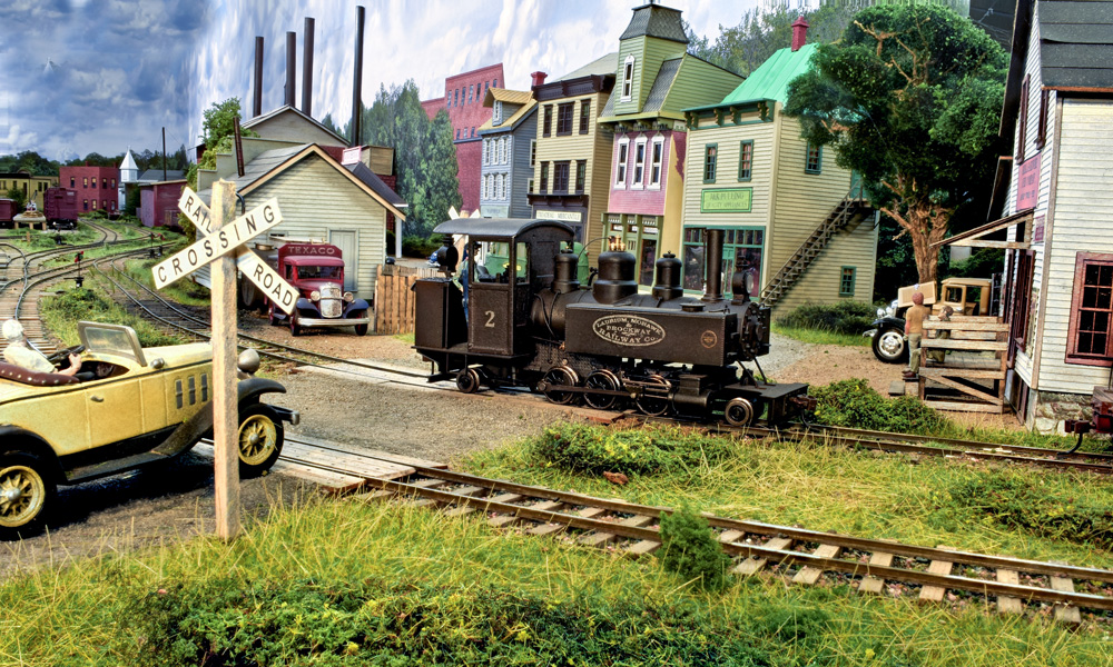 A small tank engine rolls past a bucolic small town