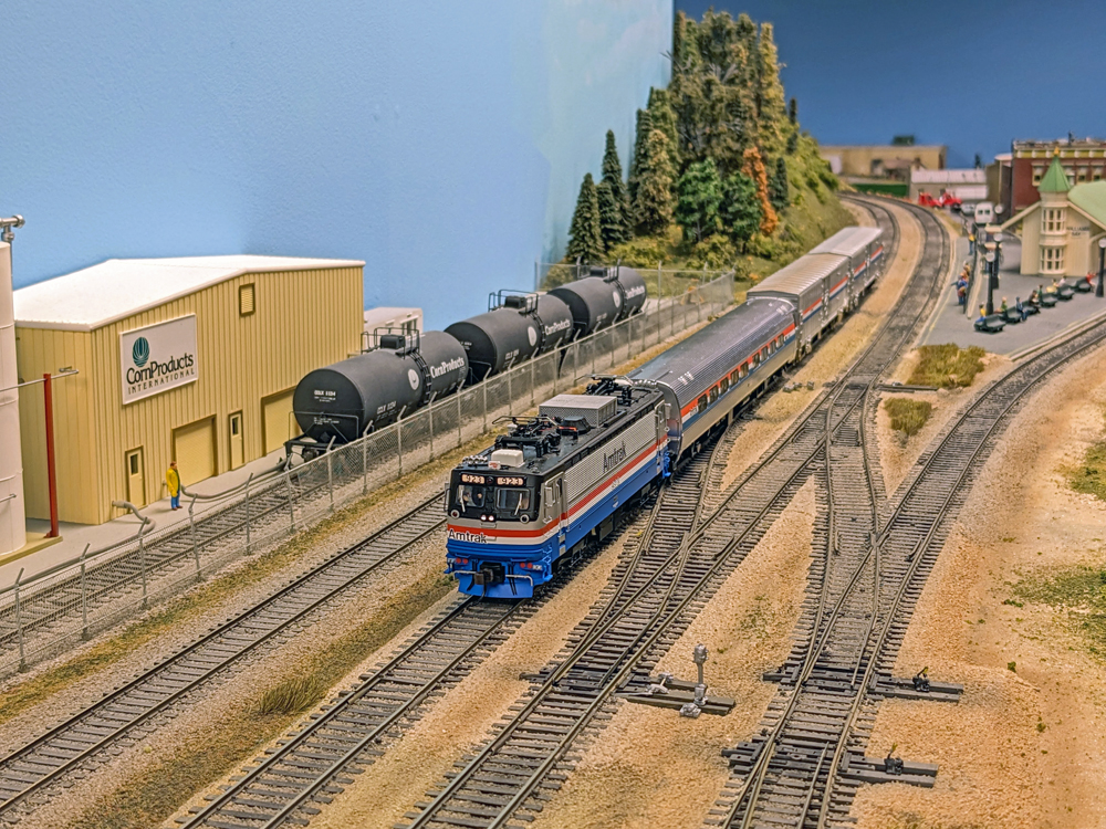 Model passenger and freight train enters a train yard.