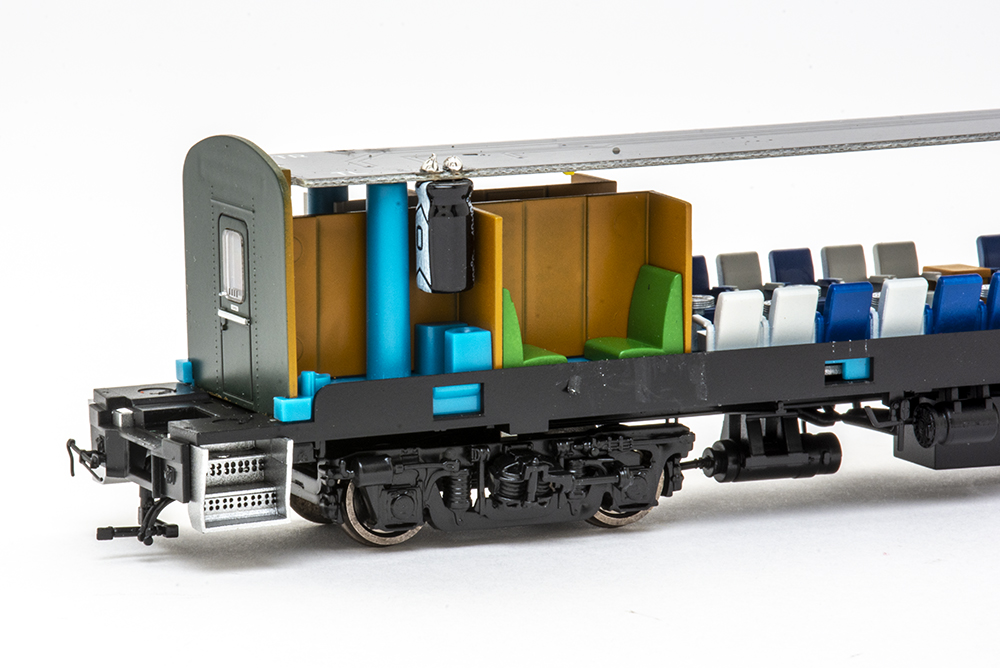 Interior view of a model train passenger car with blue, brown, green and black plastic parts