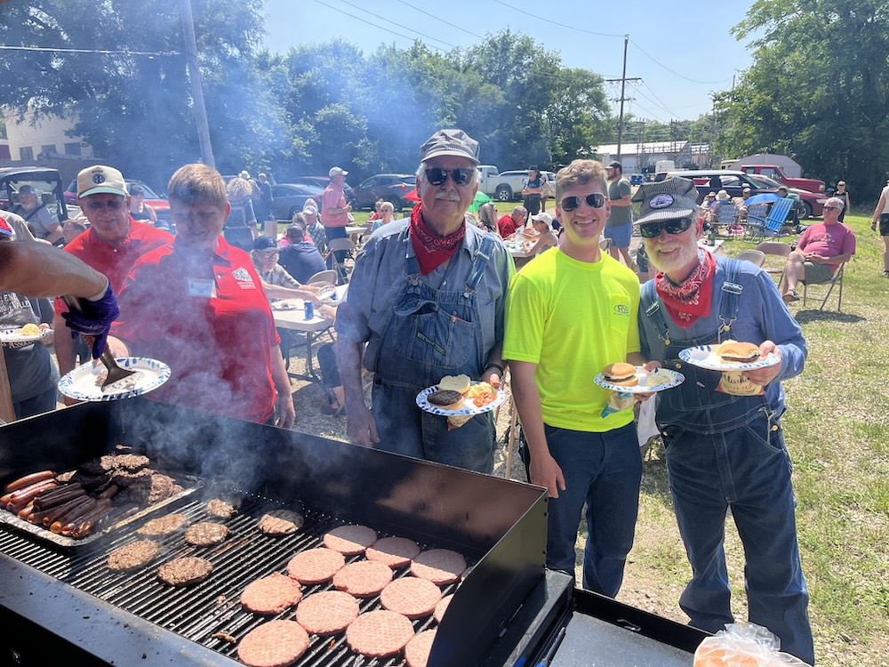 Crew posing in front of grill during celebration