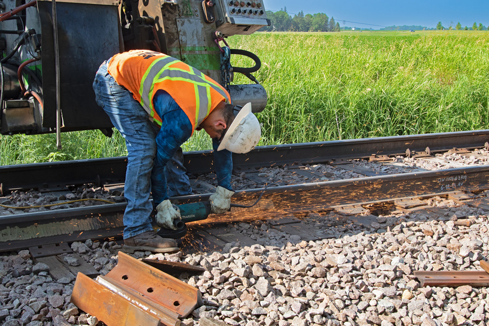 Man bent over rail with machine sending out tail of sparks