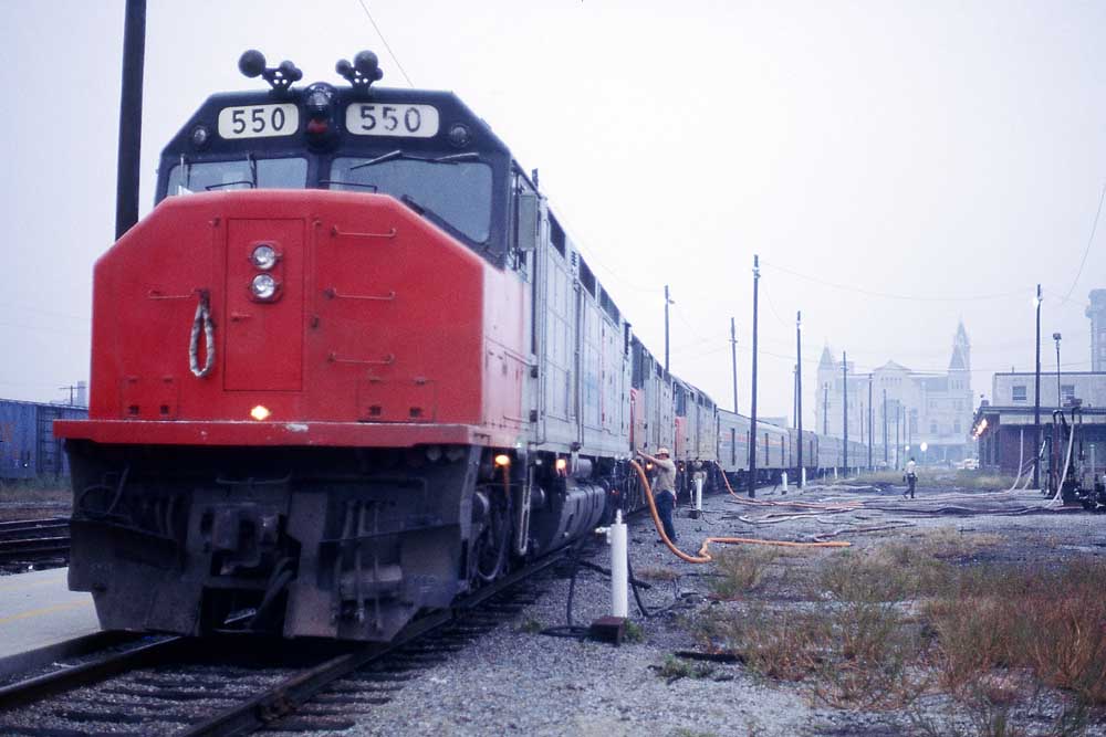 Red-and-black diesel locomotive with Amtrak Floridian passenger train at station