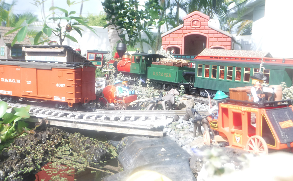 scene on garden railway with wagon, car, and station