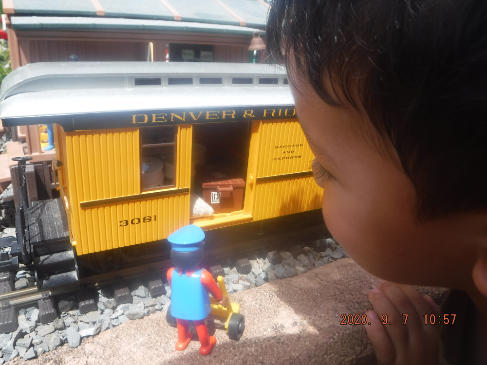 child peers inside yellow piece of model rolling stock