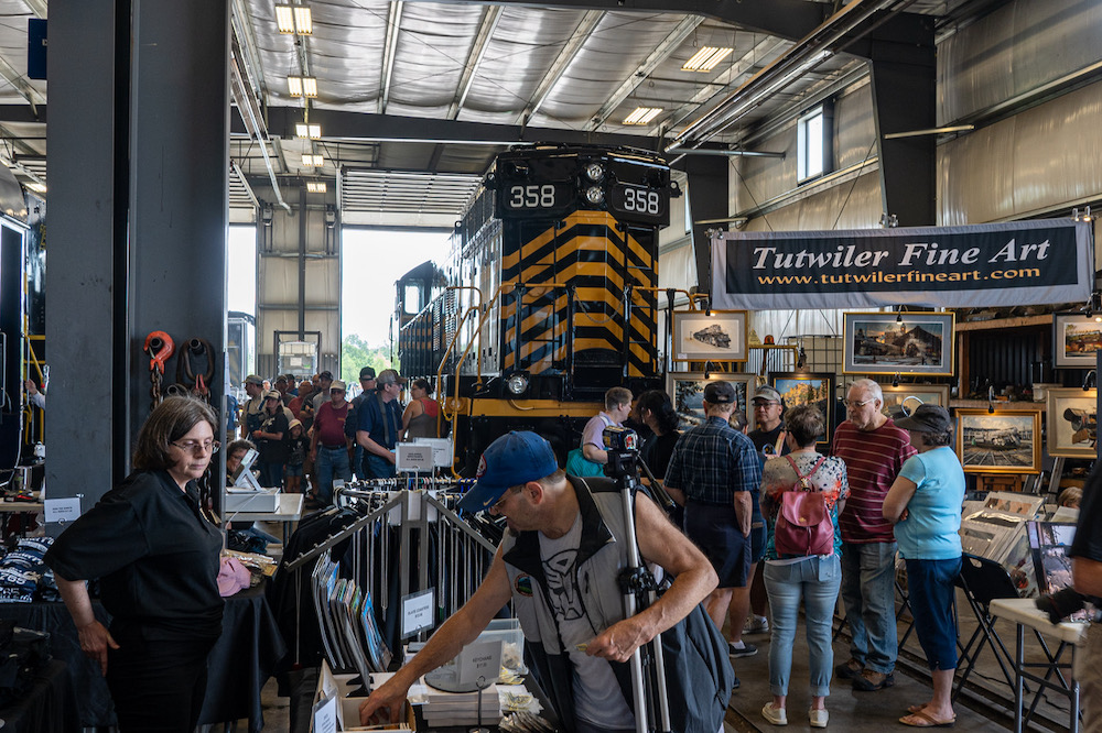 Large crowds inside locomotive facility with a diesel on display.