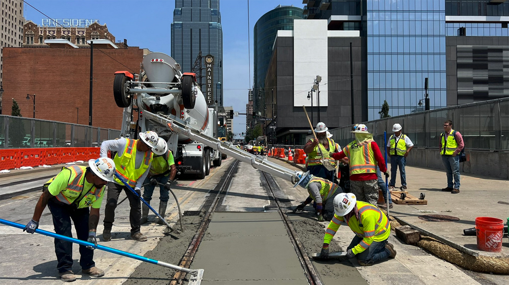 Workers pouring concrete between rails on street bridge