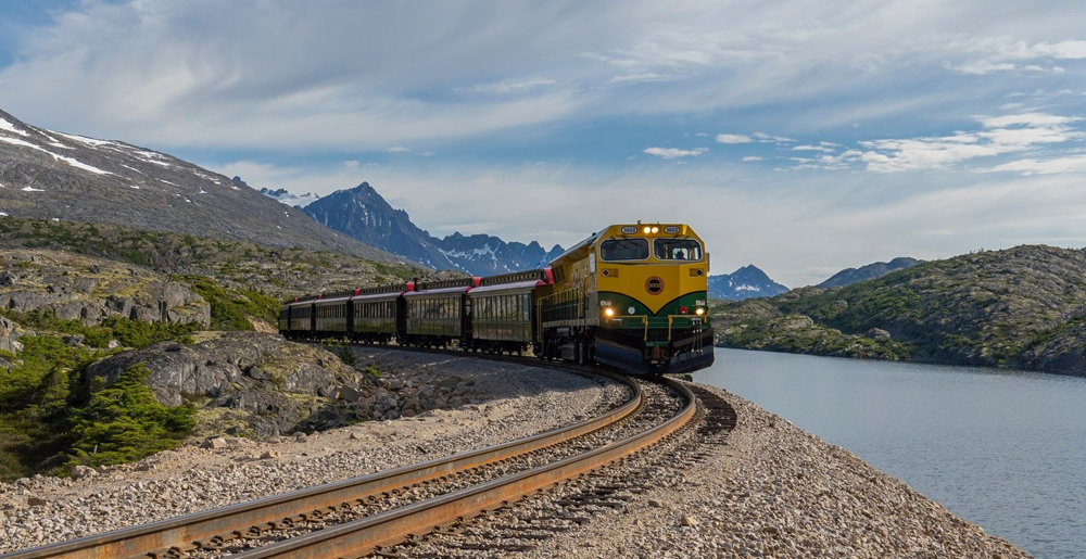 Yellow and green diesel with vintage-style passenger cars on narrow-gauge track