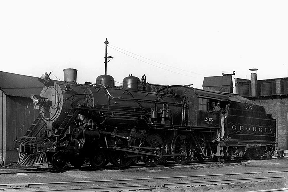 Steam locomotive in front of shop building