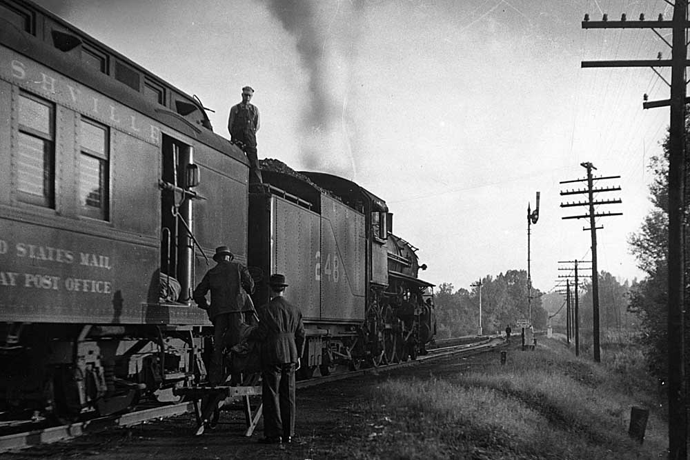 Men loading baggage behind steam locomotive