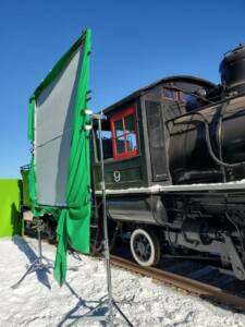 Screen on tripod setup beside steam locomotive cab