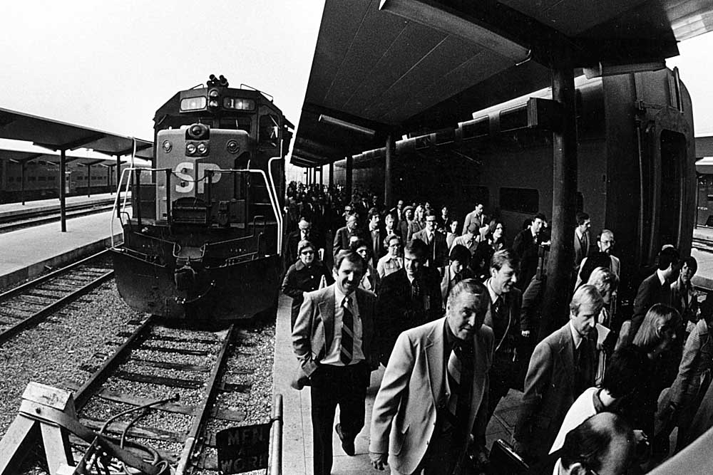 People walking past diesel locomotive in passenger station