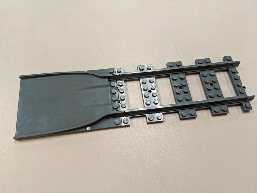 A LEGO train track ramp and piece of train track
