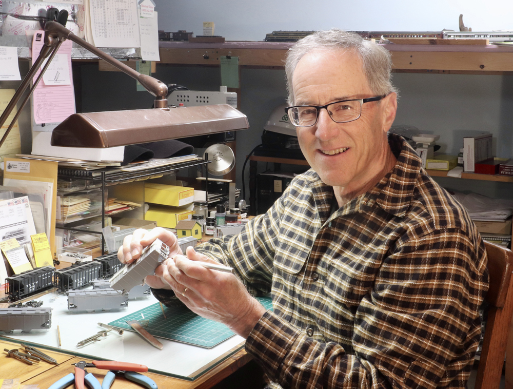 man holding model while sitting at workbench
