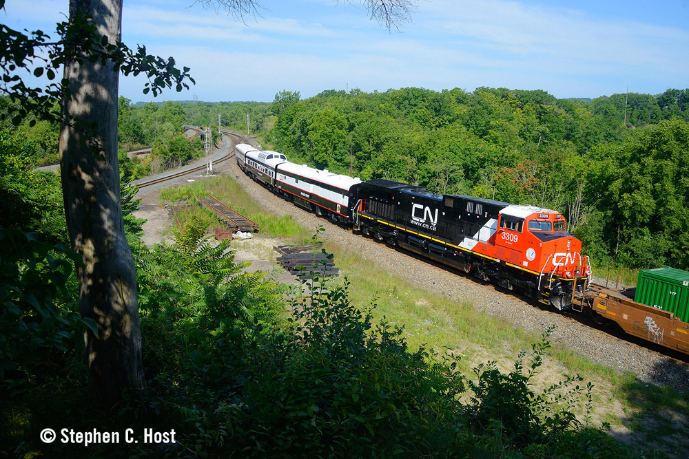 Red and black locomotive and three passenger cars on end of intermodal train