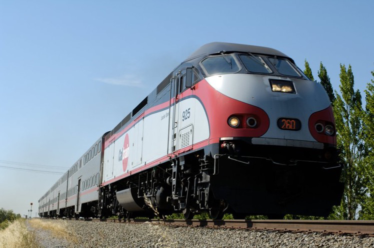 Red, white, and black diesel with bilevel commuter cars