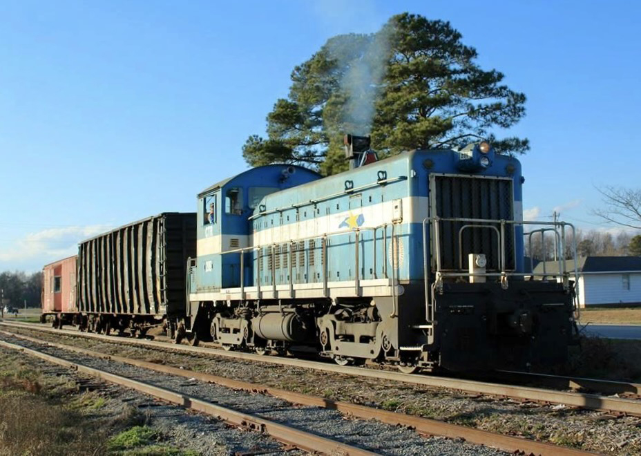 Green and white end-cab switcher with one car and caboose