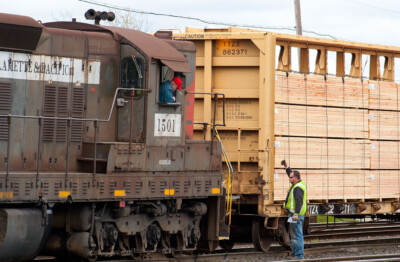 Gray and red SD7 switching carload of lumber