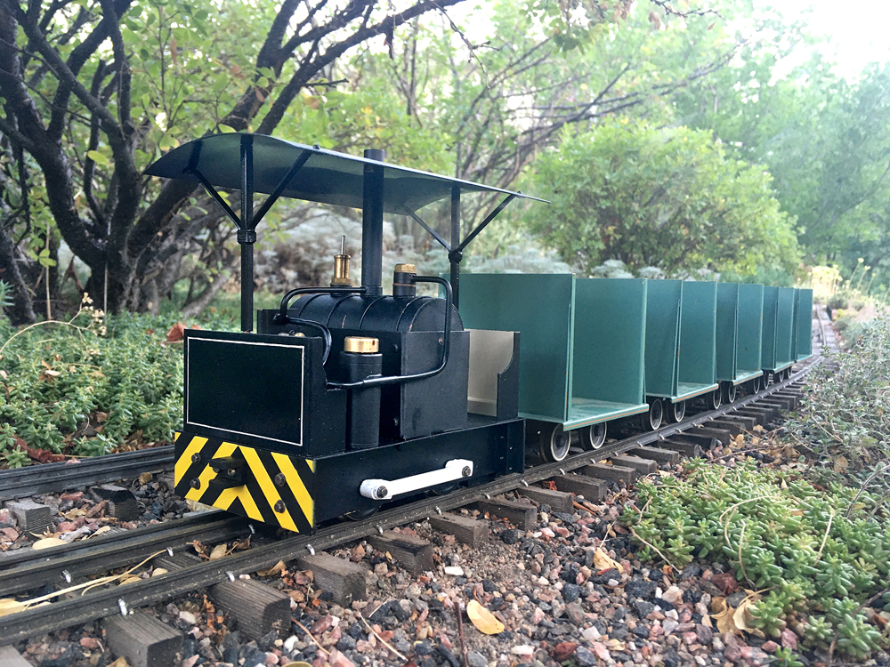 green tram engine with cars on a garden railroad