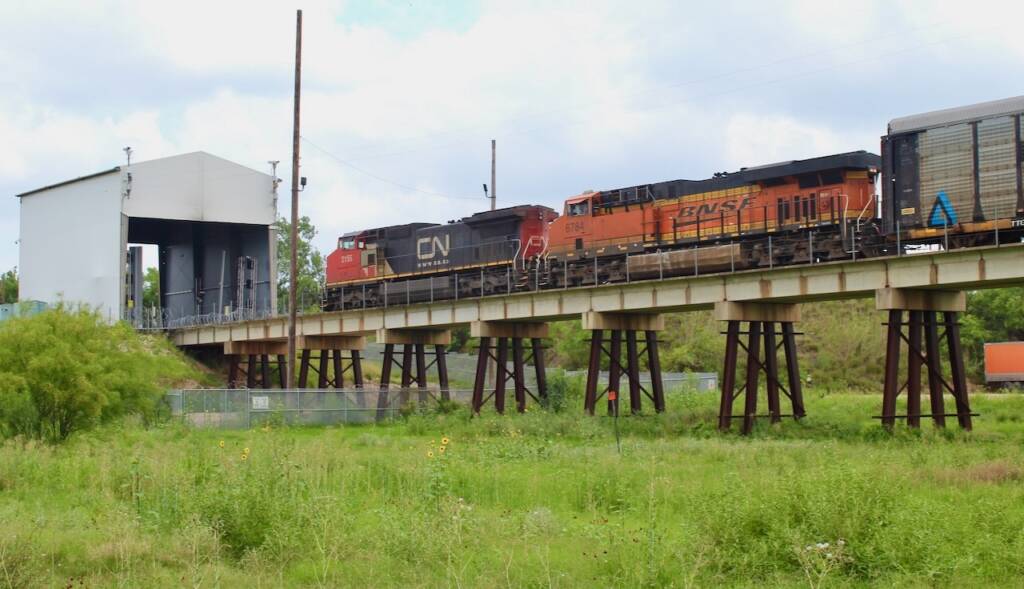 Train on bridge approaching small building covering tracks