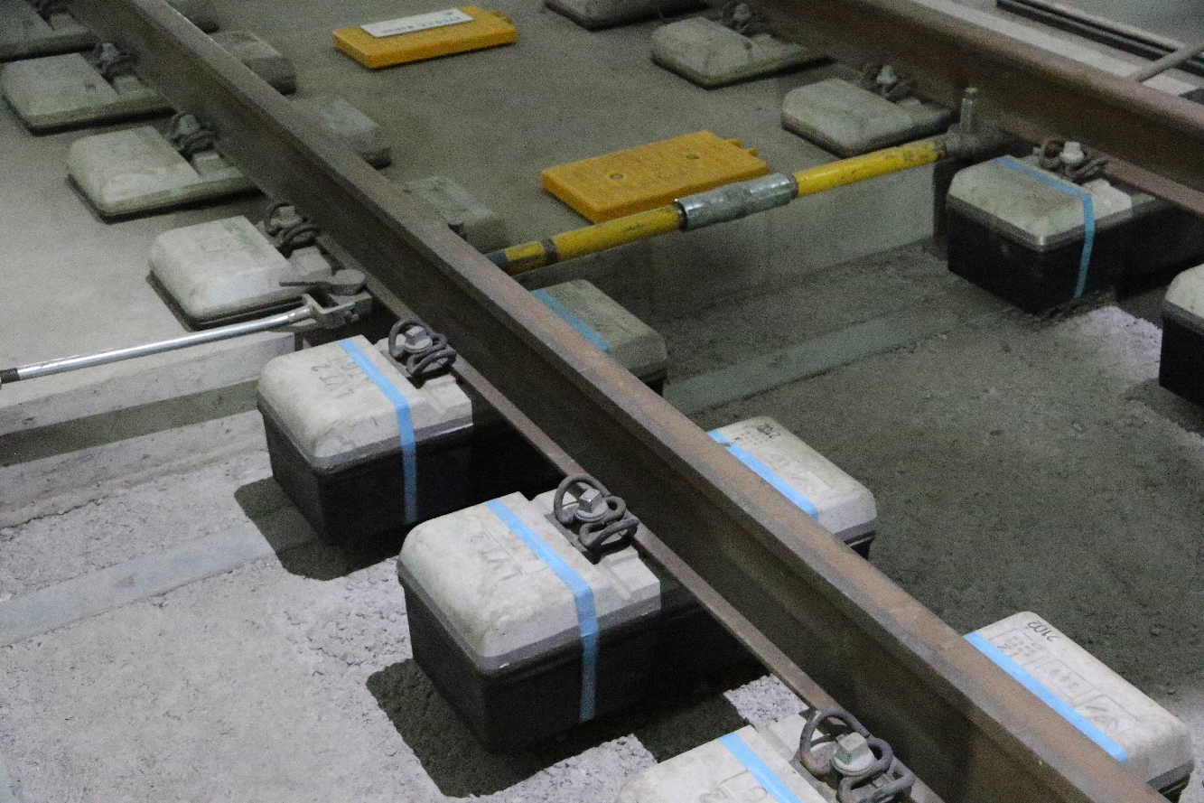 small concrete tie under one rail of a train track