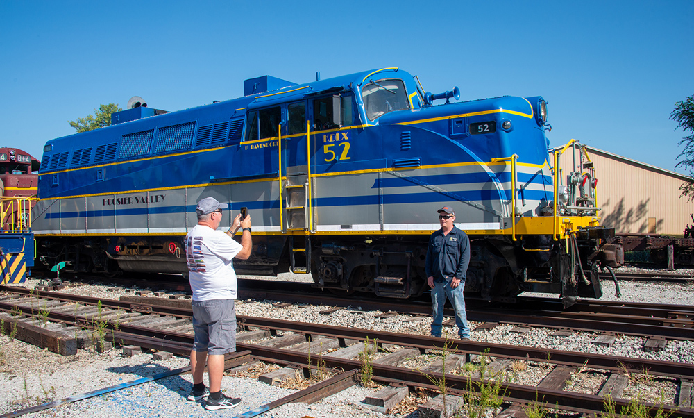 photographer taking picture of guy in front of engine