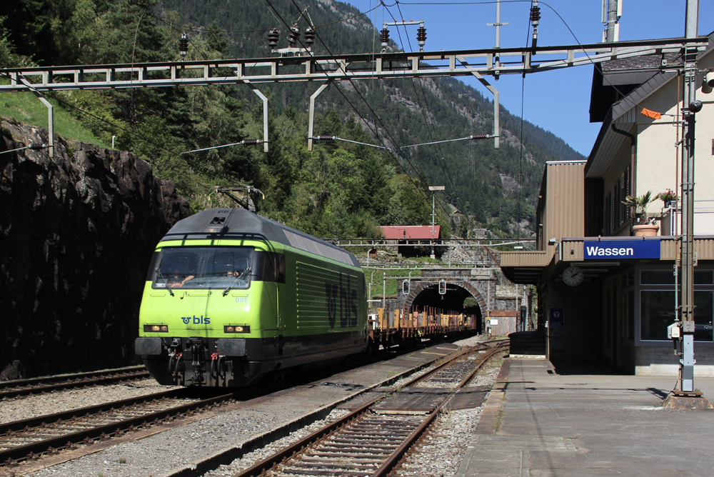 Freight train with bright green engine passes station