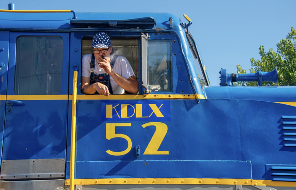 Man smoking cigar out of cab window of diesel locomotive
