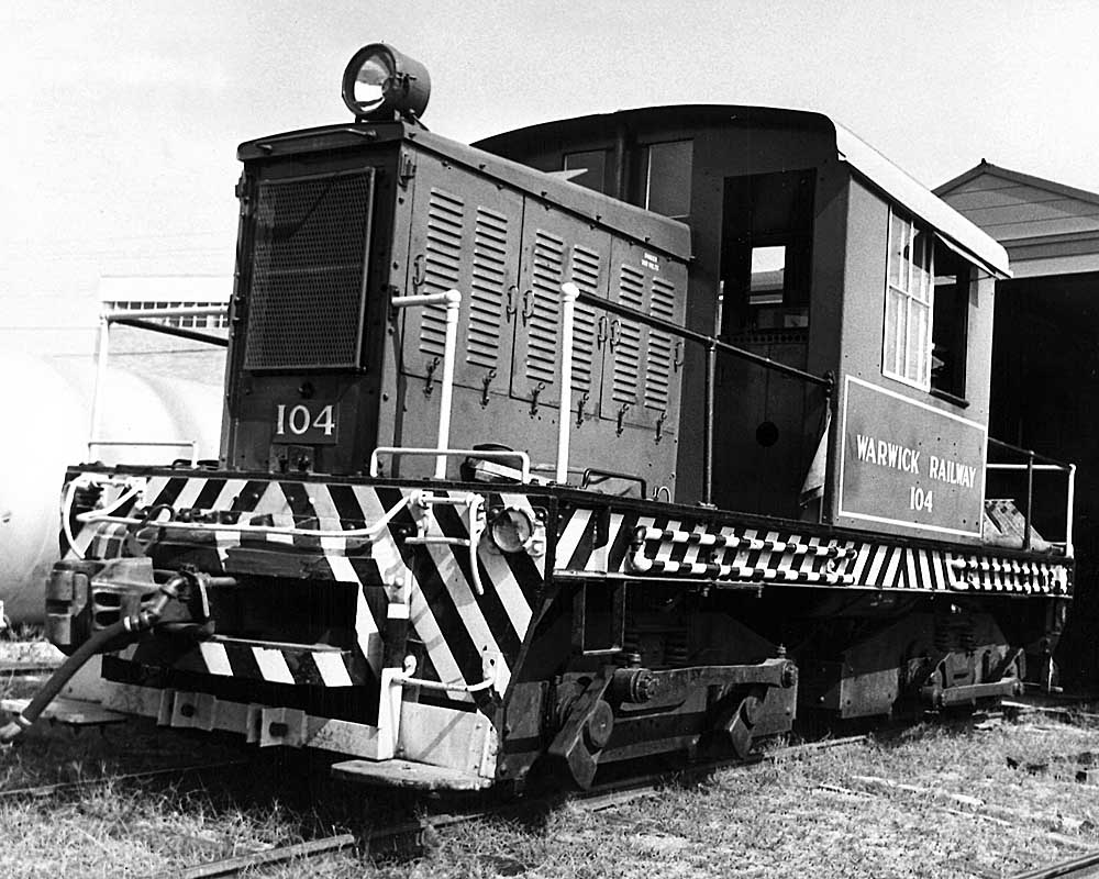 Centercab diesel locomotive in front of engine shed