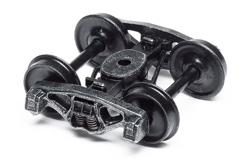 A weathered model railroad truck with plastic wheels on a white background