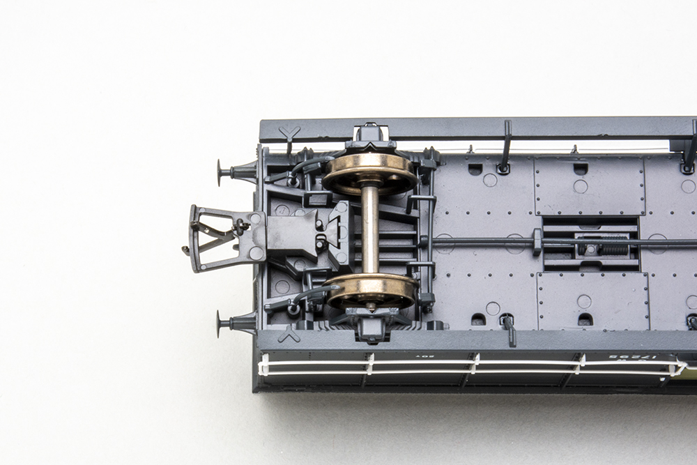 Rapido UK brake van: Bottom of model British train wagon showing a pair of silver wheels and a black hook and loop coupler.