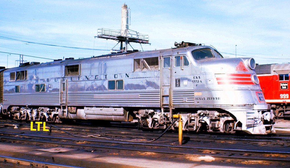 A chrome silver passegner locomotive is seen in a railroad maintenance terminal