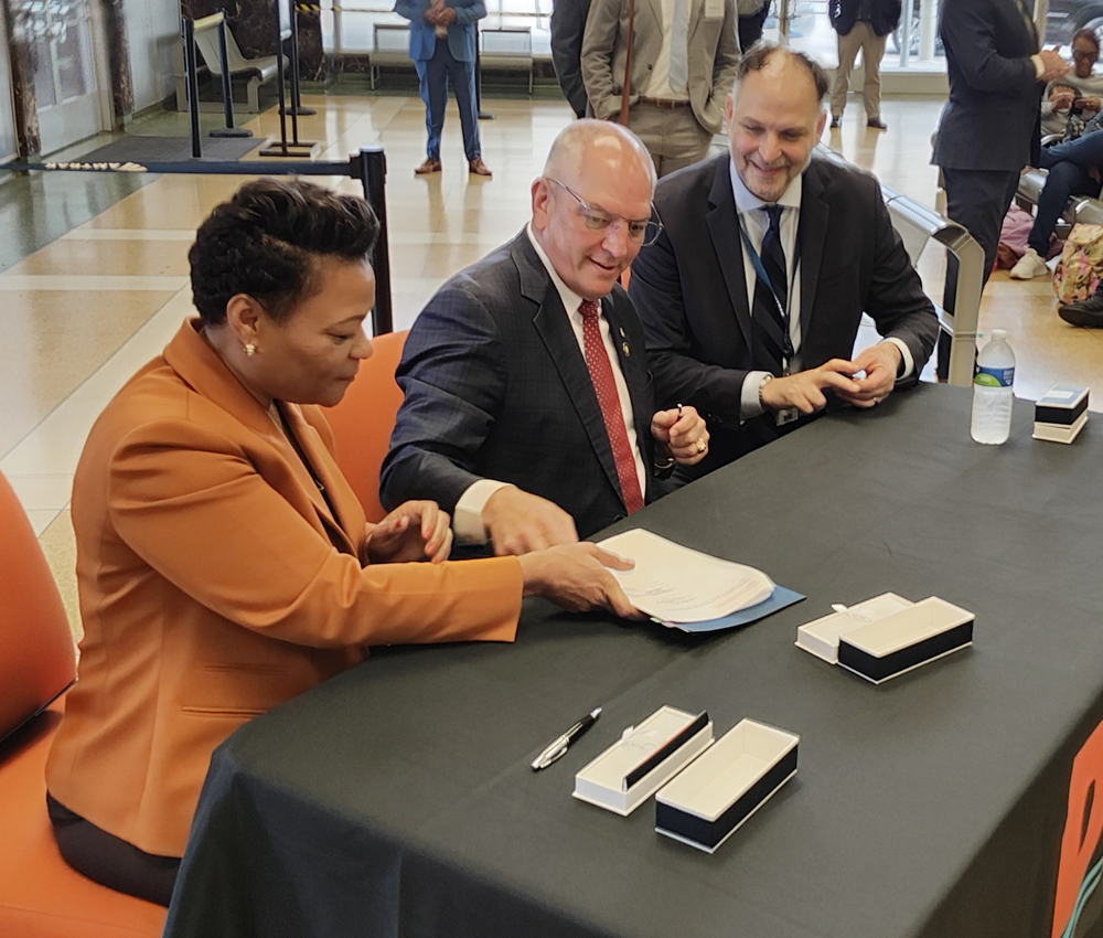 Woman in orange clothing at table with two men.