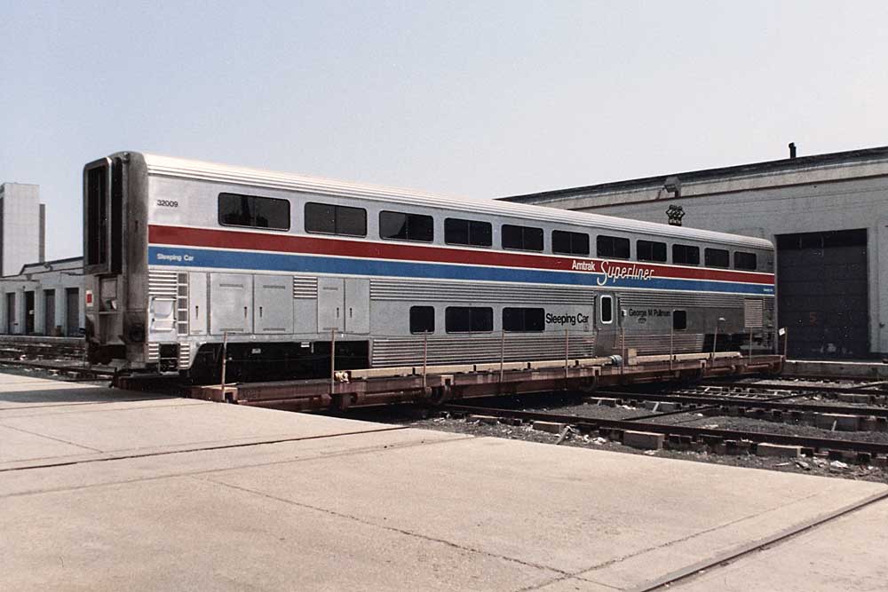 One of hundreds of Amtrak Superliner cars outside a building at the factory