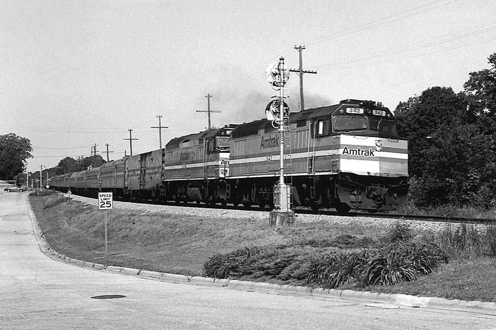 overnight Amtrak trains with two locomotives passing signal along street