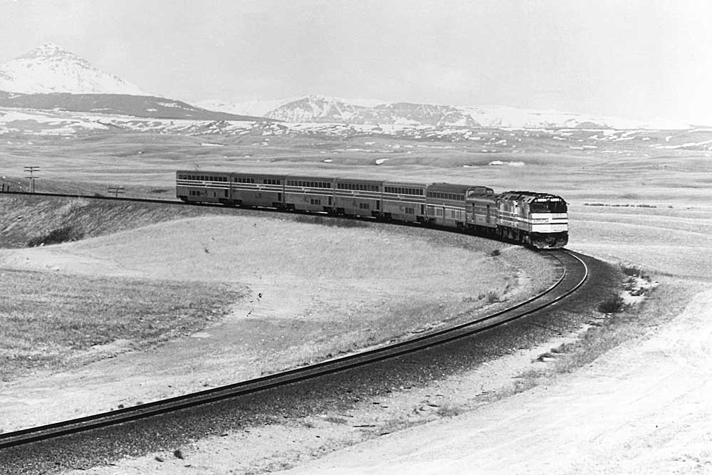 overnight Amtrak trains with two locomotives and seven cars on curve in front of mountains