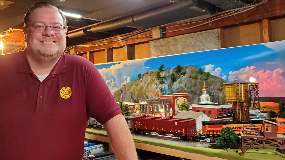 man standing next to train layout