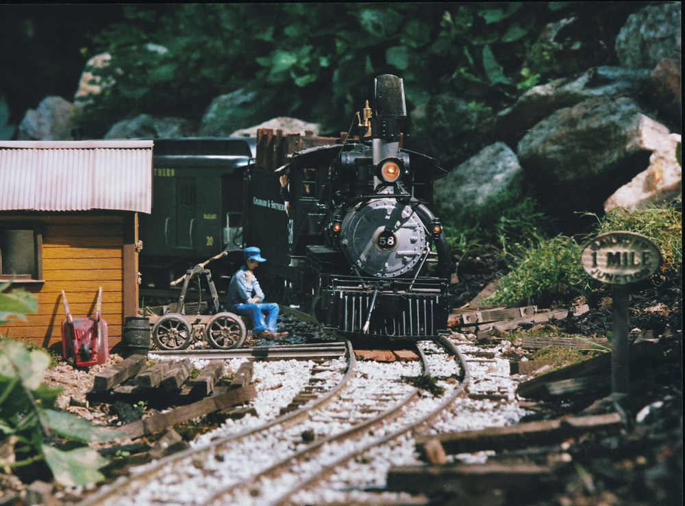 Model train near station on garden railroad