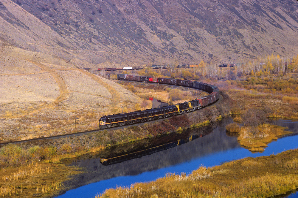 train going around curve by lake