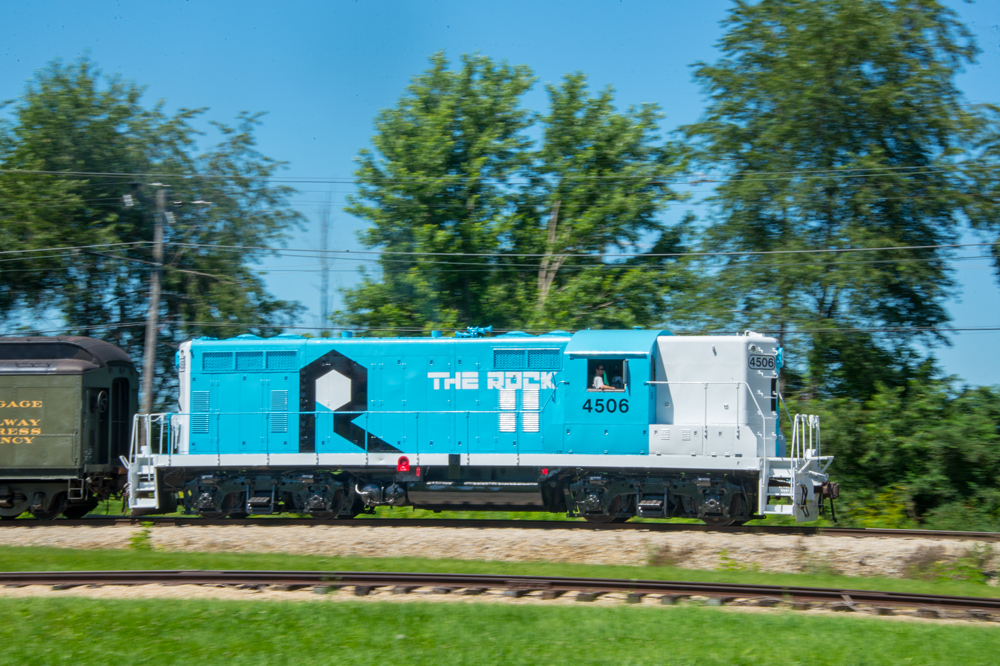 blue and white locomotive with trees behind it