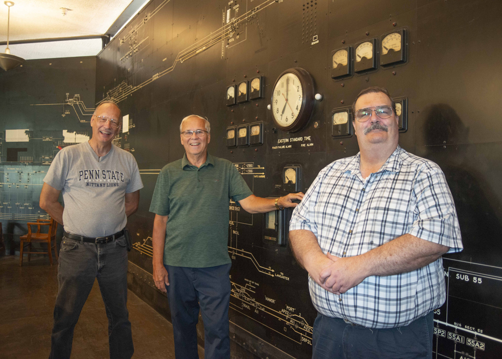 Three men in front of displays at power office