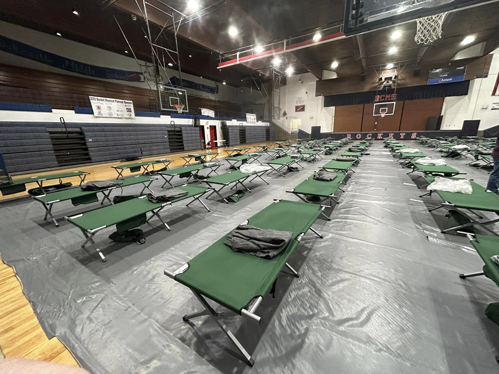 School gymnasium with cots lined up on floor