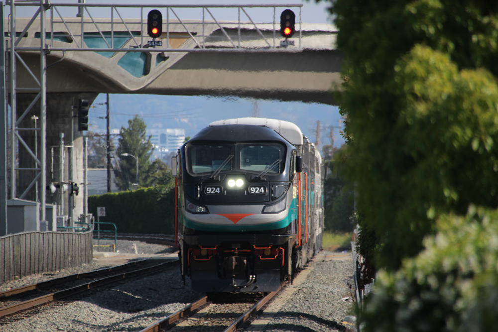 Commuter train passes under signal bridge