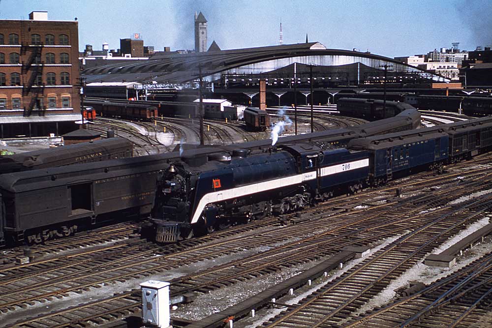 Blue-and-white steam Wabash locomotives with passenger train at curved-roof station