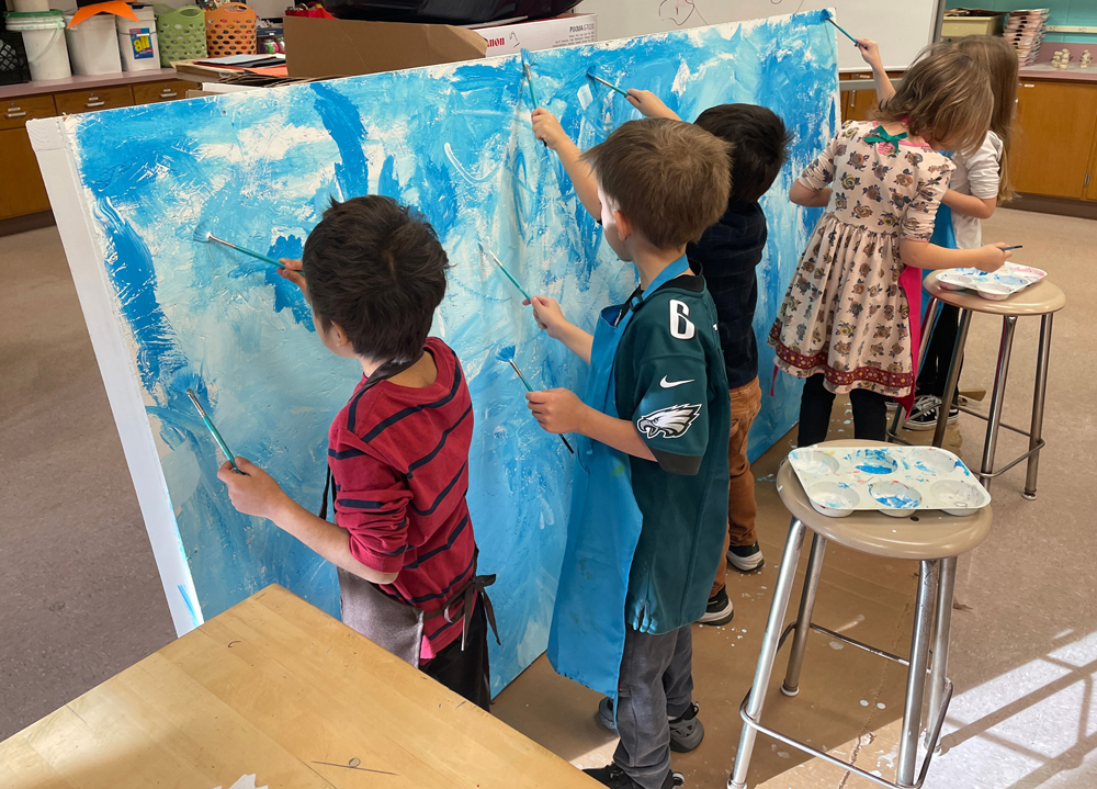 four children painting a backdrop: Elementary school toy train layout