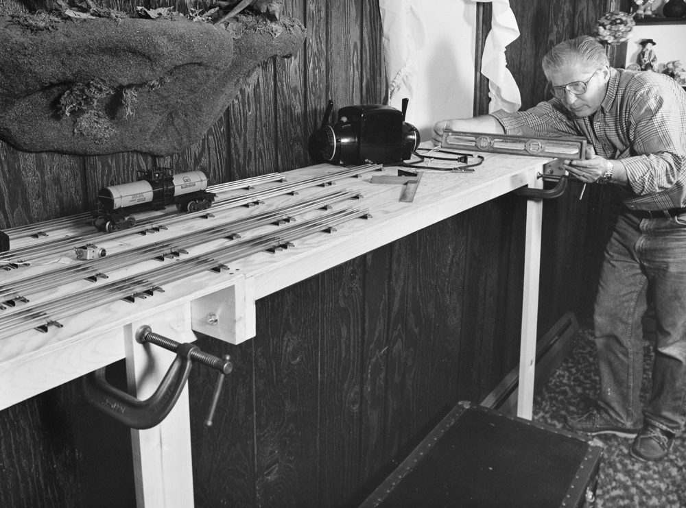 older man watching train on layout