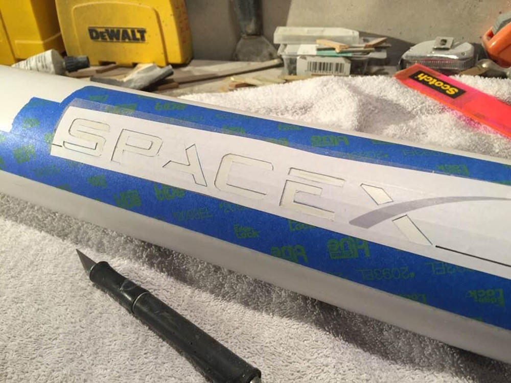 piece of model rocket with stencil taped to it
