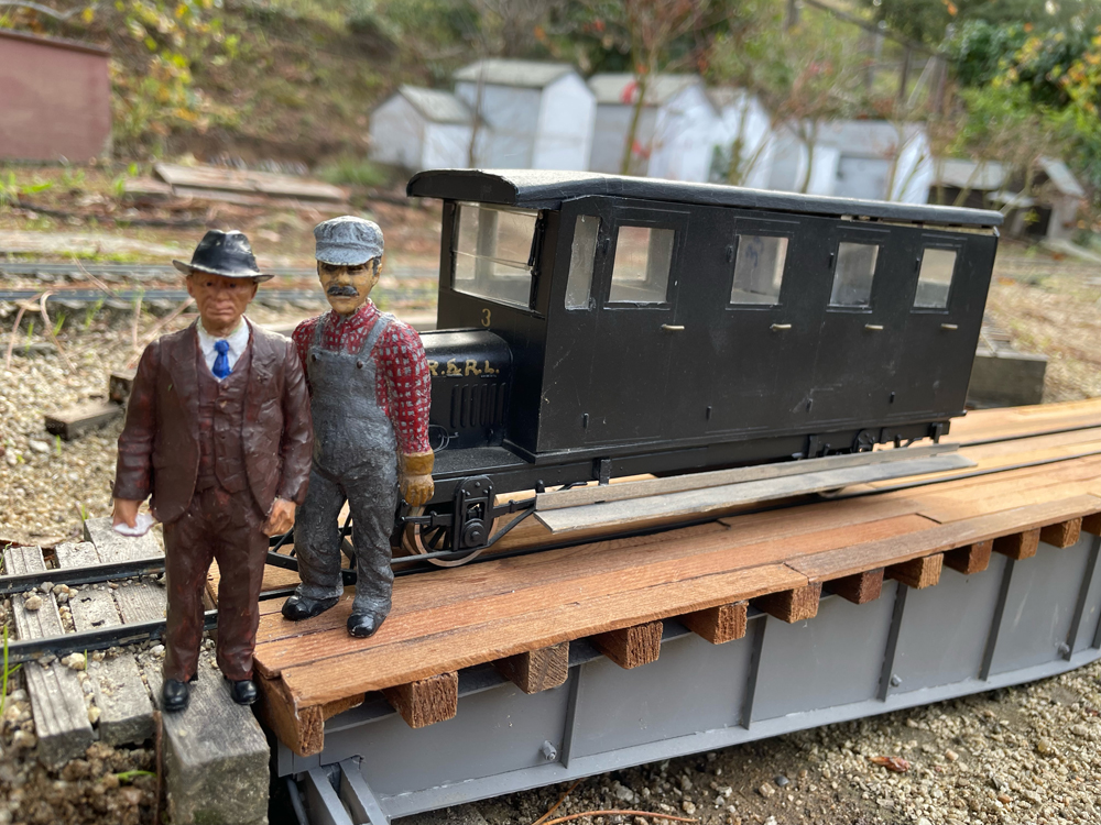 two figures next to rail car on garden railway