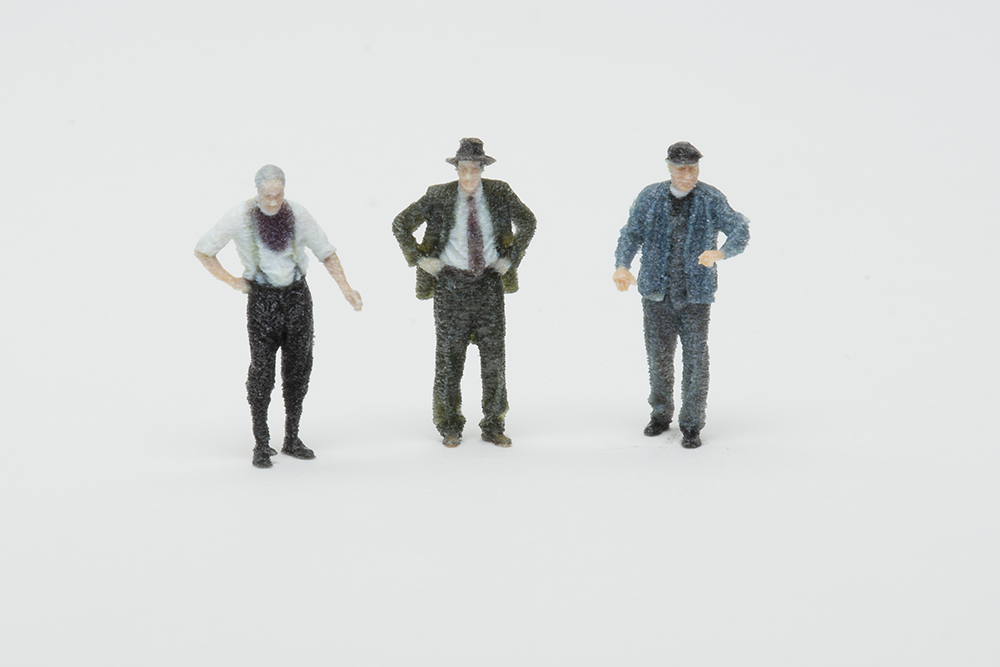 Rapido UK Titfield Thunderbolt: Three small plastic people used for model trains, dressed in blue, brown, and white clothing.