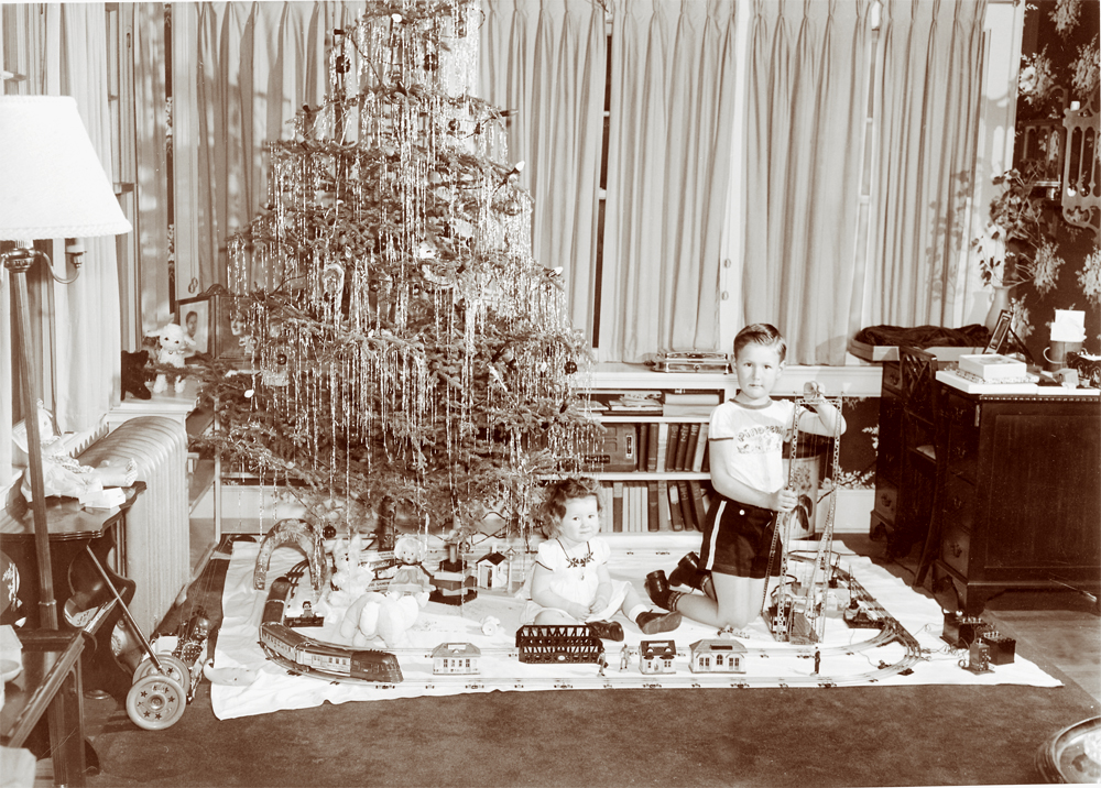 sepia picture of kids around a tree playing with toy train set