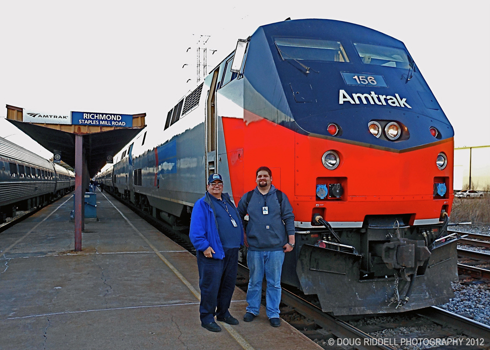 two men standing by Amtrak train on track